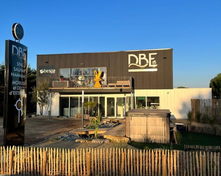 Façade extérieure de la boutique DBE85 à Saint Hilaire de Riez, Vendée, spécialisée dans la distribution des spas Be Spa. L'enseigne de la boutique est clairement visible, avec une vitrine élégante présentant des modèles de spas et des affiches publicitaires.